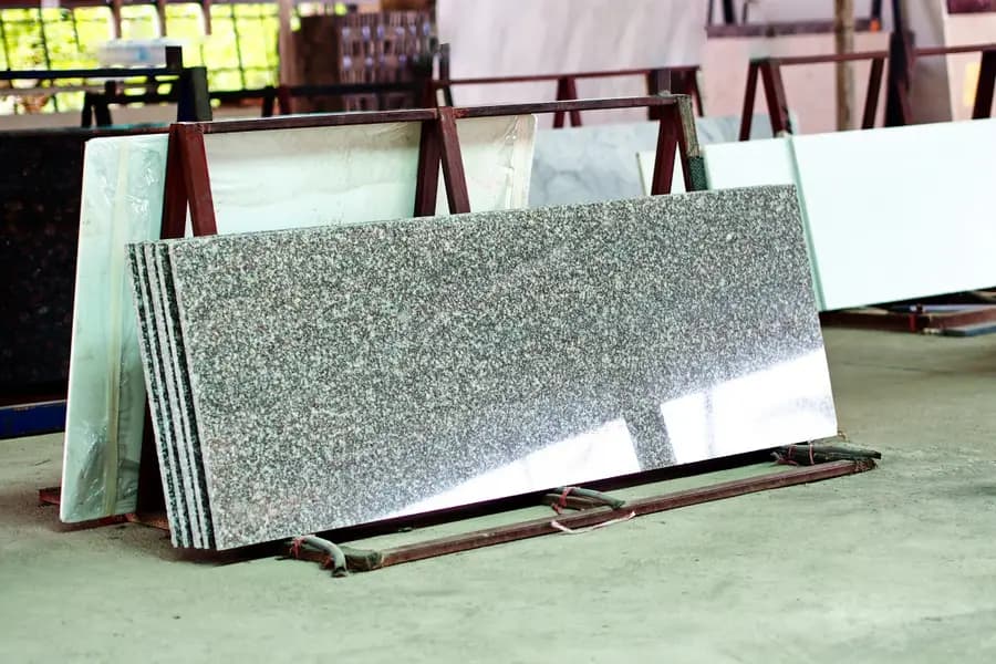 Losas de piedra y cuarzo cortadas, apoyadas en estantes dentro de un taller de fabricación.